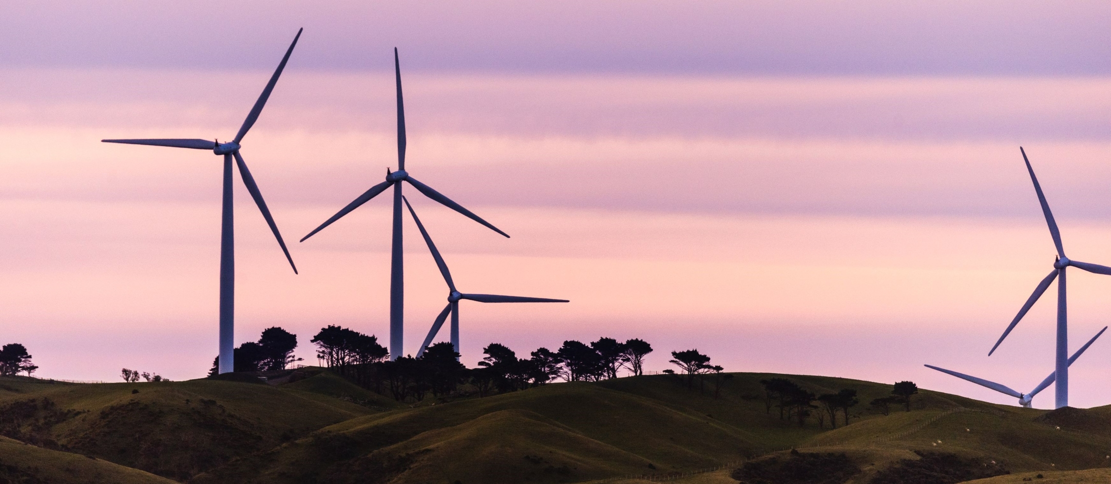 Wind farm with five wind turbines against a sunset sky